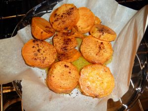 sweet potato slices being roasted on parchment paper