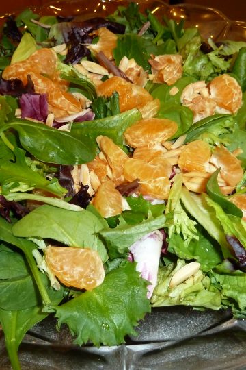 Almond and clementine salad on a clear plate