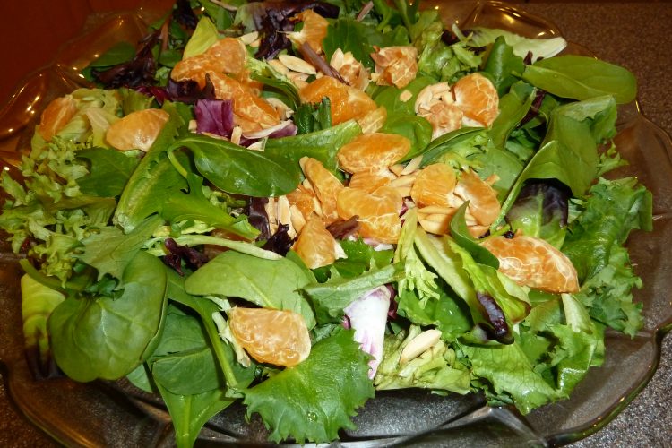 Almond and clementine salad on a clear plate