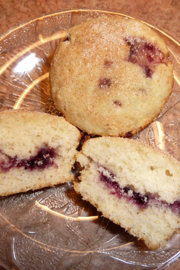 Baked doughnuts on a plate, one cut in half to show off its jelly centre