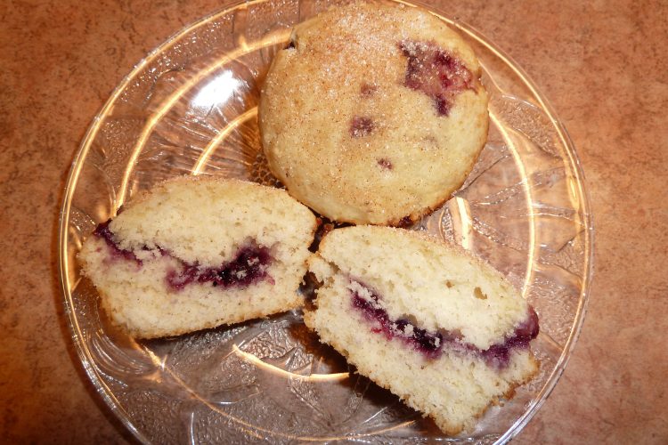 Baked doughnuts on a plate, one cut in half to show off its jelly centre