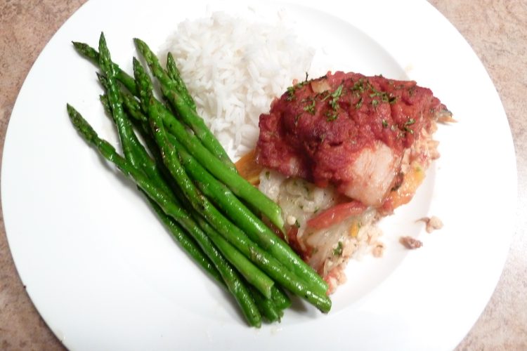 Baked stuffed salmon with asparagus and rice on a white plate