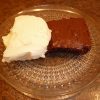 shows a chocolate brownie on a plate with a side serving of ice cream