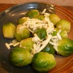 Cooked brussels sprouts topped with Asiago cheese