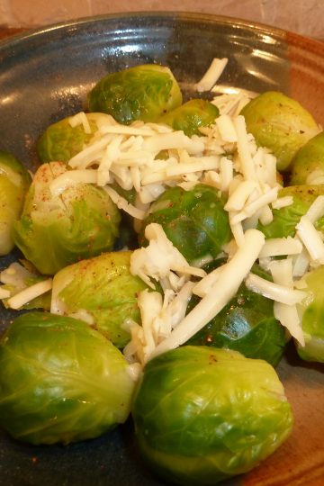 Cooked brussels sprouts topped with Asiago cheese