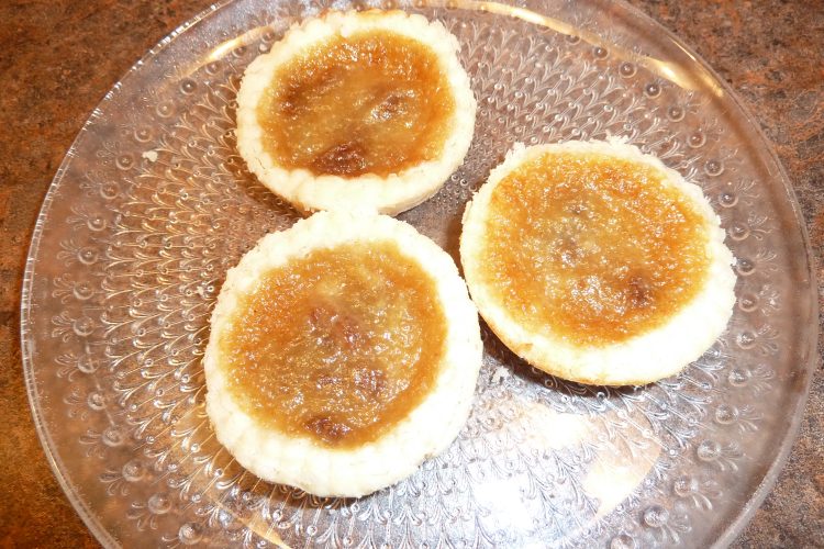 Three butter tarts on a plate.